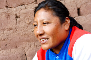 Happy aymara woman. House wall background.