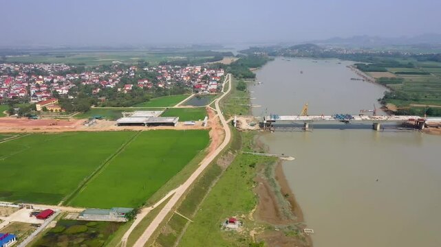 Flycam to&agrave;n cảnh c&acirc;y cầu đang thi c&ocirc;ng bắc qua s&ocirc;ng, drone bay ngang, ghi lại c&ocirc;ng tr&igrave;nh v&agrave; cảnh quan xung quanh.