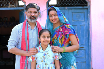 Indian beautiful rural happy family of father, mother and daughter sitting together at the house...