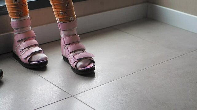 cild with cerebral palsy waring special shoe trying on walk indoor 