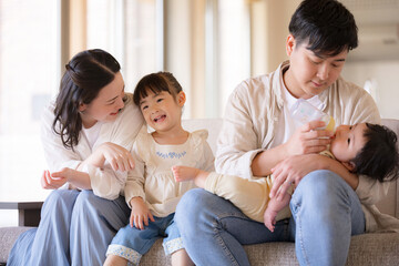 木のぬくもりのある新築のような家の自宅のソファーでくつろぐ4人の日本人家族　幸せ家族のイメージ