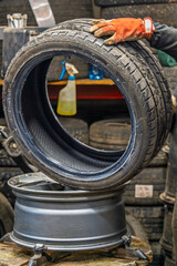 Automotive Tire Replacement Service with Professional Tire Mounting Machine in Garage Workshop. Mechanic Hands Operating Specialised Equipment for Seasonal Tire Change Process