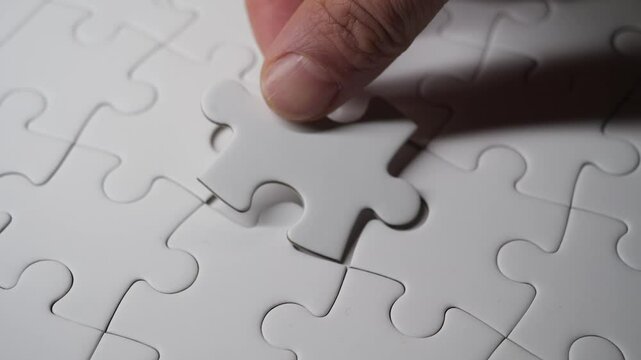 A hand placing a puzzle piece into its final spot, completing the jigsaw.