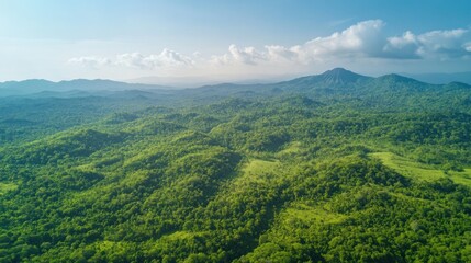 Lush green hills and mountains stretch into a hazy horizon under a vibrant sky