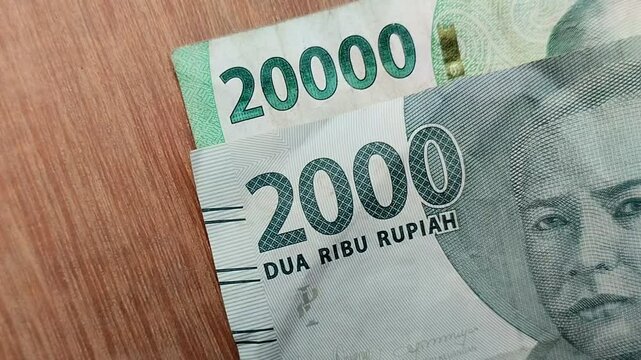 two thousand rupiah and twenty thousand rupiah on a wooden texture background. Indonesian currency (IDR). economic concept