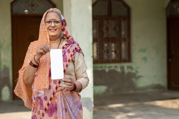 Portrait of Indian old woman showing showing unique identity card at village. Indian senior rural woman showing Aadhar card at home. Concept of rural woman empowerment in india.