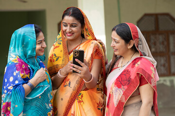 Group of Indian rural women using phone in village. Concept of Rural Digital Technology in India