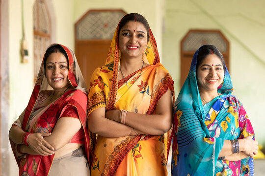 Concept of Women Empowerment in India. Group of Indian rural women wearing traditional sari standing cross arms at village home.