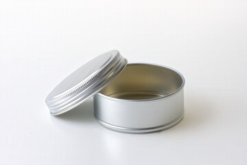 Open silver metal tin container with lid on white background
