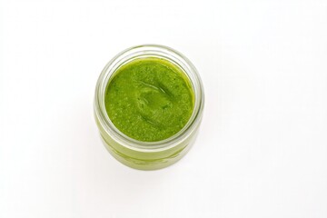 Glass jar of green sauce or chutney on white background
