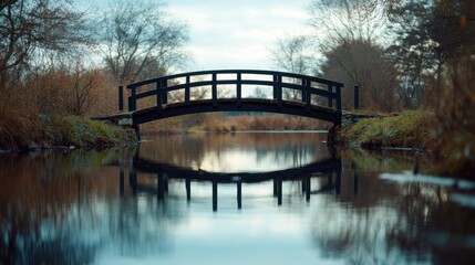 Peaceful wooden bridge over a calm stream. Autumnal scenery reflected in the water