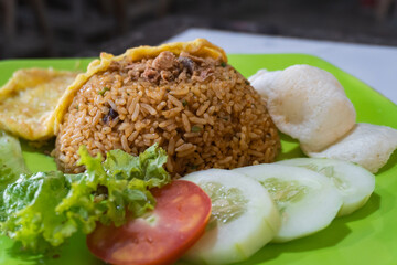 Indonesian fried rice with lettuce, tomato, cucumber and crackers. Fried rice and omelette.