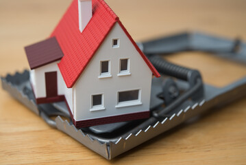 House in rat trap on wooden table background. Real estate, property, land, rental, mortgage closing...