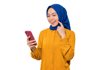 Smiling young Asian Muslim woman dressed in orange shirt looking at mobile phone screen, feels...