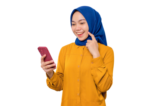 Smiling young Asian Muslim woman dressed in orange shirt looking at mobile phone screen, feels joyful reading good news isolated on transparent background