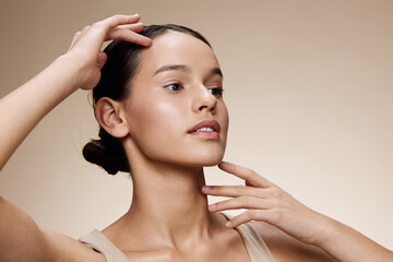 Naklejka premium A young woman with smooth skin, showcasing skincare routine, natural beauty, and self care, wearing a neutral sleeveless top against a soft beige background