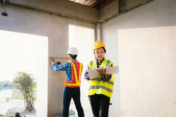 Engineers and architects collaborate at a construction site, wearing safety gear, examining...