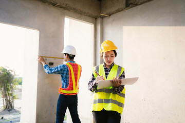 Engineers and architects collaborate at a construction site, wearing safety gear, examining...