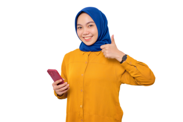 Smiling young Asian Muslim woman dressed in orange shirt holding mobile phone and making thumb up gesture, approve good thing isolated on transparent background