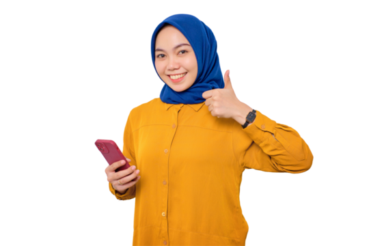Smiling young Asian Muslim woman dressed in orange shirt holding mobile phone and making thumb up gesture, approve good thing isolated on transparent background