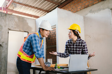 Engineers and contractors inspect construction plans indoors, using technology and equipment to...