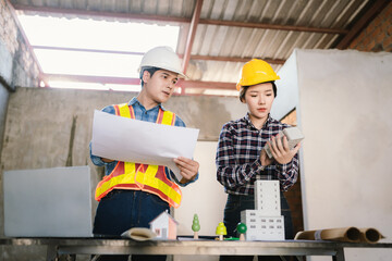 Engineers and contractors inspect construction plans indoors, using technology and equipment to...