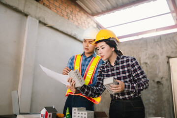 Engineers and contractors inspect construction plans indoors, using technology and equipment to...