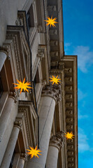 Fototapeta premium Leuchtende Weihnachtssterne an der prachtvollen Fassade eines denkmalgeschützten ehemaligen Bankgebäudes in Berlin-Mitte