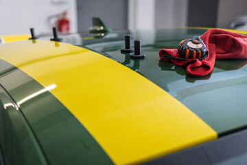 Tools used in the installation of self-adhesive film stickers. Yellow sticker on a green car....