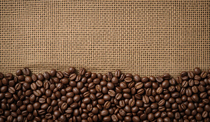 Fototapeta premium Roasted coffee beans fill the bottom of the frame against a burlap background. Rich, dark, and aromatic, perfect for coffee lovers.