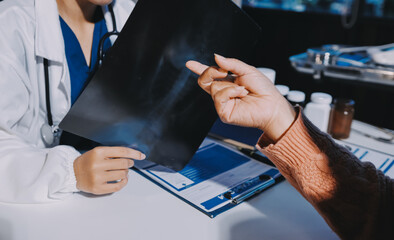 The doctor explain the old lady in retired life patient on lungs x-ray film and discuss treatment...