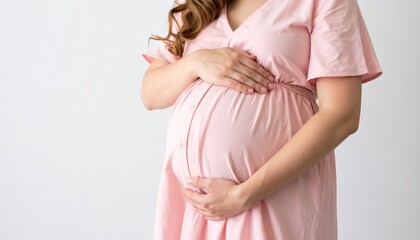 A woman in a pink dress cradles her pregnant belly, symbolizing motherhood and nurturing in a serene setting