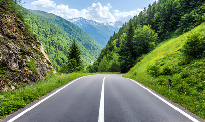 Fototapeta premium Winding asphalt road through a vibrant green mountain valley under a blue sky