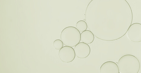 close-up view oil and water droplets forming patterns in pale green  liquid under magnification textured background.