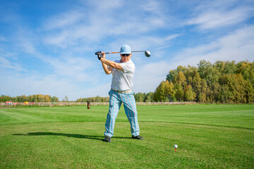 A Golfer is Swinging Enthusiastically on a Beautiful Sunny Day at the Golf Course