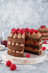 Naked chocolate raspberry cake with chocolate cream filling on a board on a concrete background.