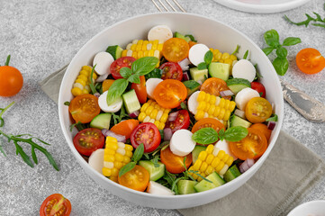 Sweet corn salad with arugula, tomatoes, cucumber, red onion and mozzarella. Healthy food. Top view.