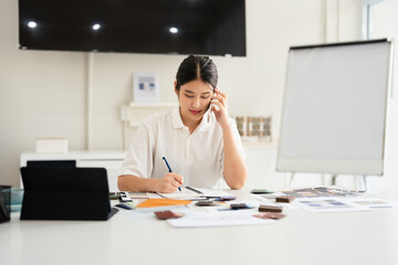 Interior designer talking on cellphone with client, discussing new project, In studio office with...