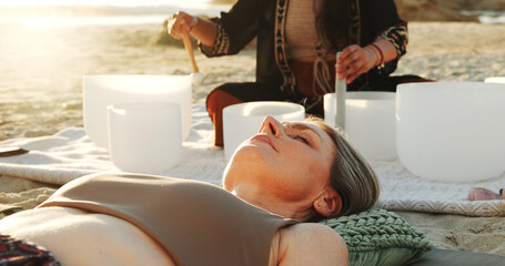 Meditation, sound therapy and women with bowls at beach for mindfulness, spiritual cleanse and...