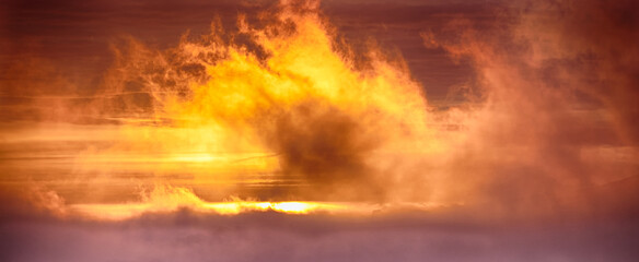 Firey orange sunrise in misty clouds