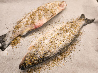 Two fresh fish seasoned with salt and herbs ready for baking