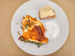 Omelette with spinach, cheese, bread and yogurt on white plate for breakfast