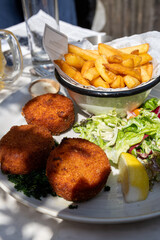Lunch in cafe with vegetarian cheese and green asparagus croquettes served with fresh salad and french fries potato in Bruges, Belgium