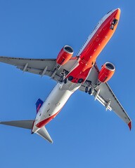 A modern aircraft gliding effortlessly through a bright, cloudless sky, with its sleek fuselage and powerful engines visible against the clean blue backdrop.