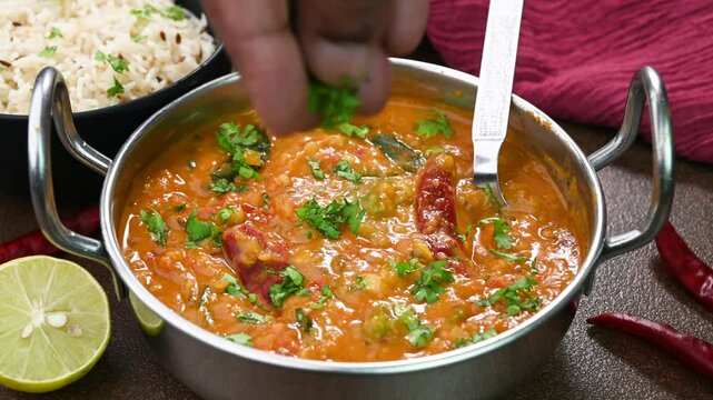 Adding coriander leaves to Dal Fry dish.