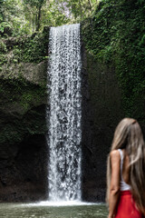 Tourist admiring majestic waterfall in tropical rainforest in bali