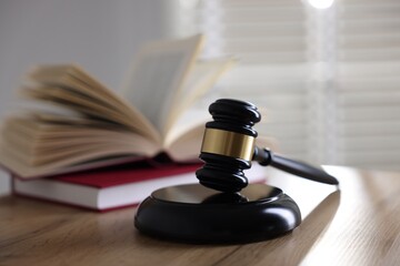 Judge's gavel and books on wooden table indoors, selective focus