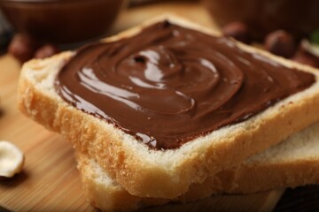 Toast with tasty chocolate spread on wooden table, closeup