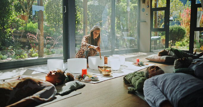 Woman, singing bowl and healing on floor for therapy, frequency and peace with mindfulness at studio. Group, shaman and holistic with guide in class, crystal and zen for chakra balance at resort