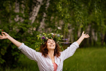Smiling woman in white shirt and flower crown on green forest background